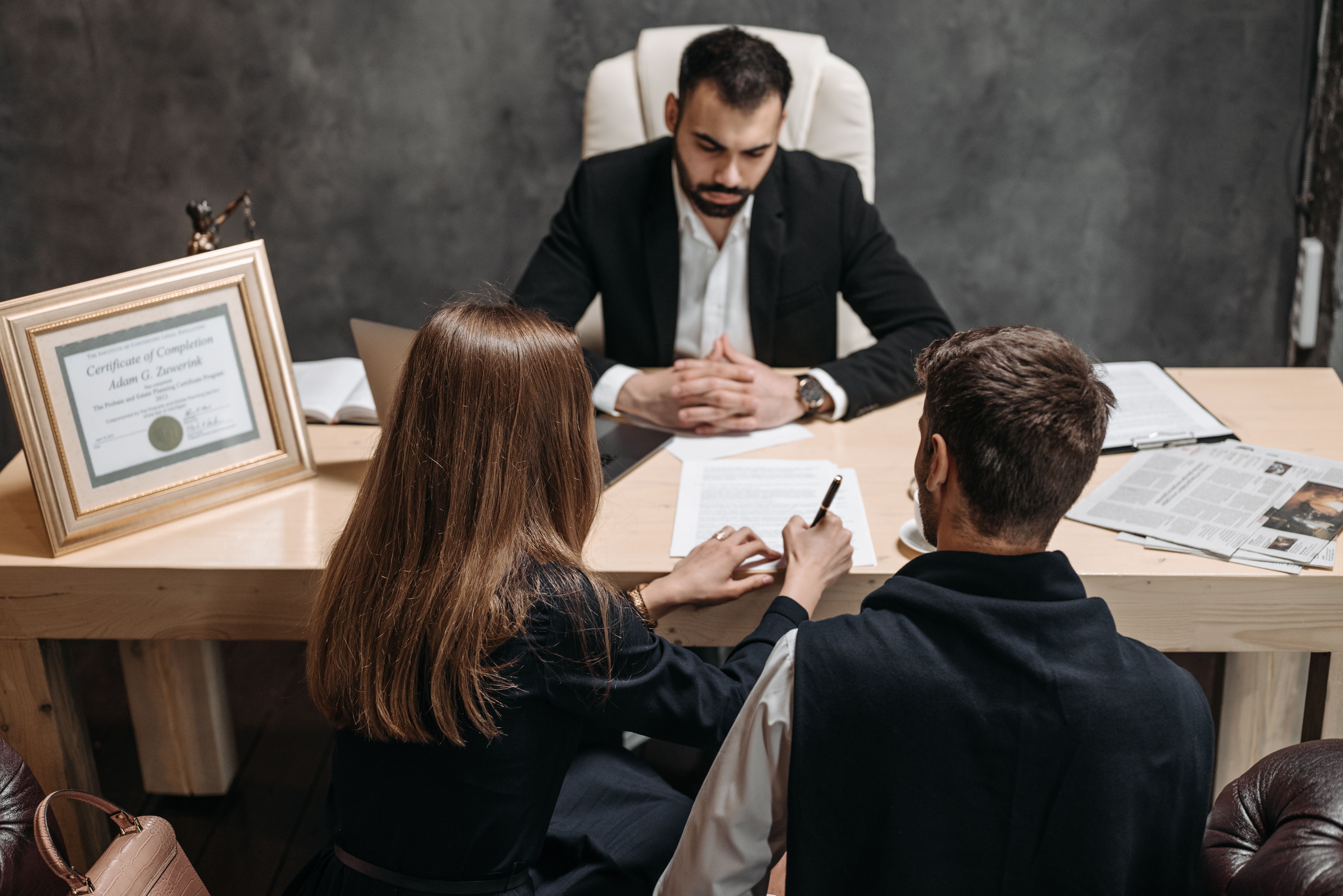 A lawyer discusses legal documents with clients in an office, explaining a litigation funding arrangement