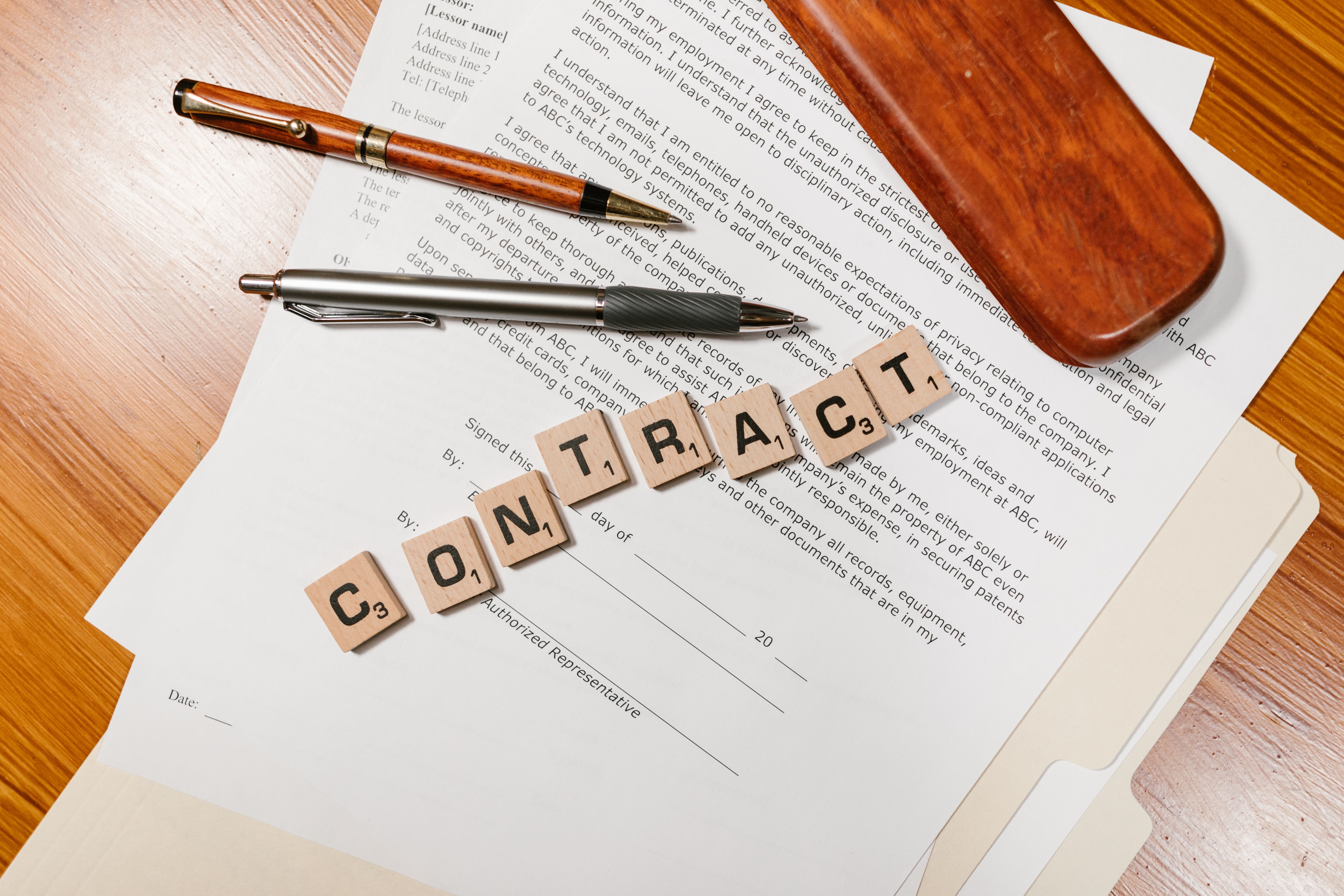 Close-up of contract papers with Scrabble tiles spelling CONTRACT, representing a litigation funding agreement structure